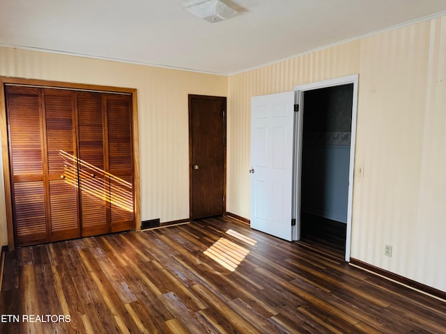 unfurnished bedroom featuring dark hardwood / wood-style flooring, a closet, and crown molding