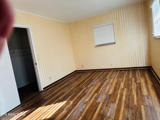 unfurnished bedroom featuring crown molding, a closet, and dark wood-type flooring