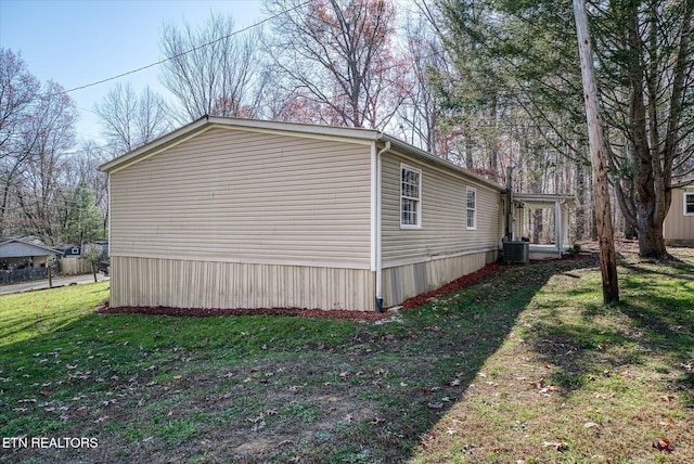 view of side of property featuring a yard and central AC unit