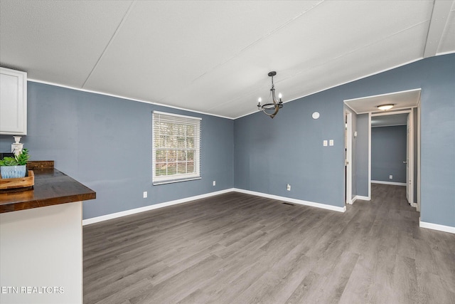 unfurnished dining area featuring a chandelier, hardwood / wood-style floors, and lofted ceiling