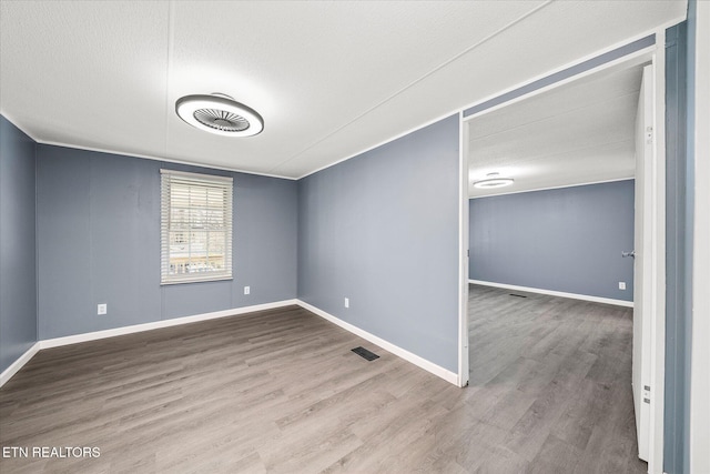 empty room with wood-type flooring and a textured ceiling