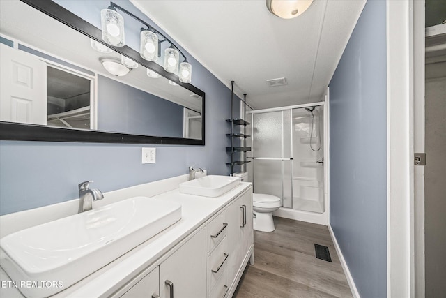 bathroom with hardwood / wood-style floors, vanity, toilet, and walk in shower