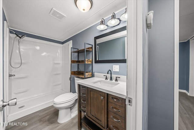 bathroom featuring walk in shower, hardwood / wood-style floors, a textured ceiling, toilet, and vanity