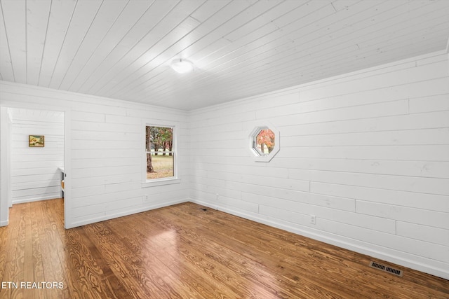 empty room with hardwood / wood-style flooring, wooden walls, and wood ceiling