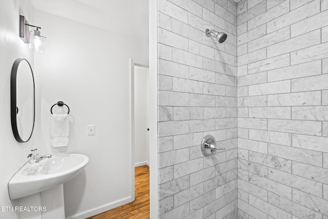 bathroom featuring a tile shower and wood-type flooring