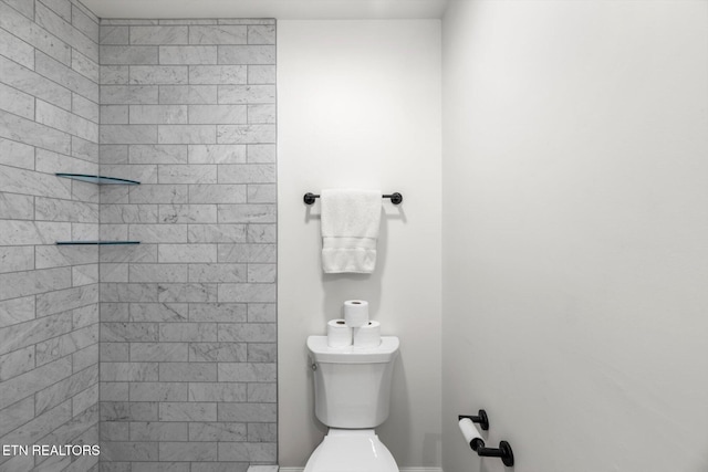 bathroom with a tile shower and toilet