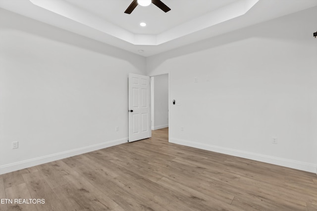 unfurnished room featuring a tray ceiling, light hardwood / wood-style flooring, and ceiling fan