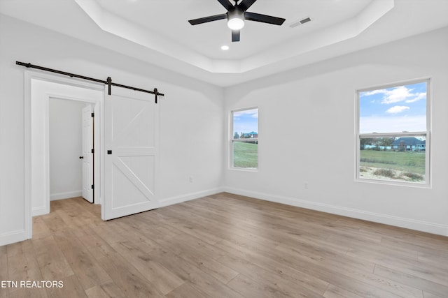 spare room with light hardwood / wood-style floors, a barn door, and a healthy amount of sunlight