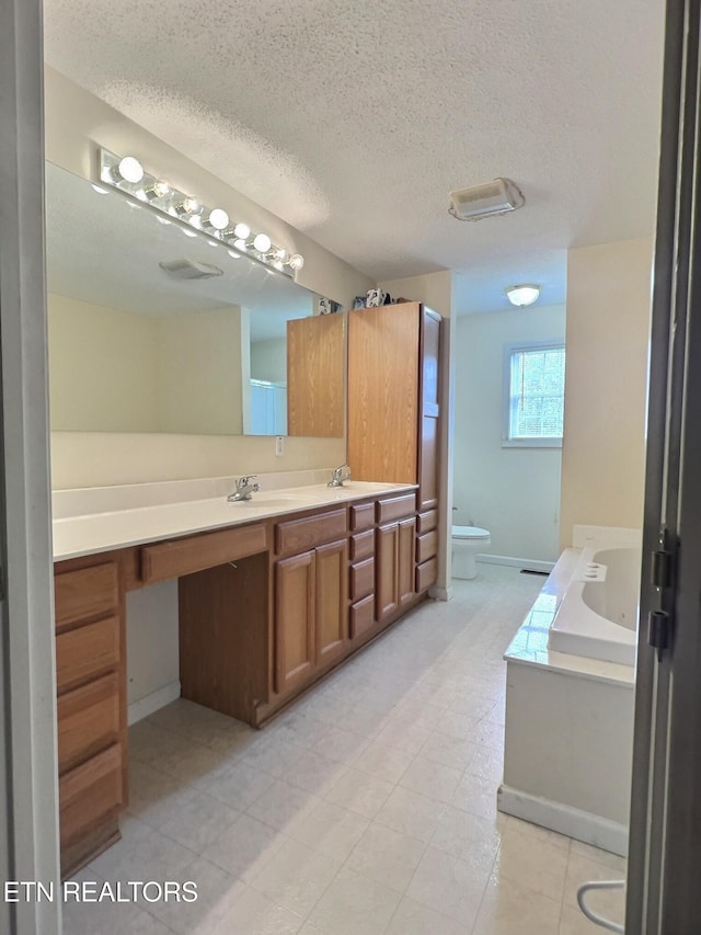 bathroom featuring a bathtub, vanity, a textured ceiling, and a bidet