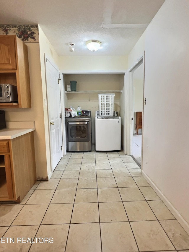 interior space with washer and clothes dryer, light tile patterned floors, and a textured ceiling