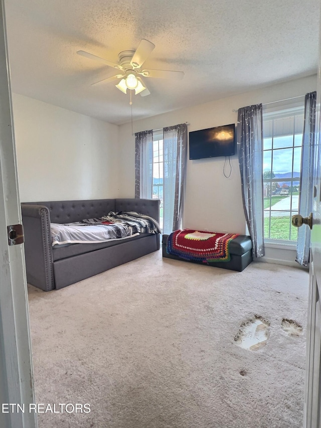 bedroom featuring carpet flooring, a textured ceiling, and ceiling fan