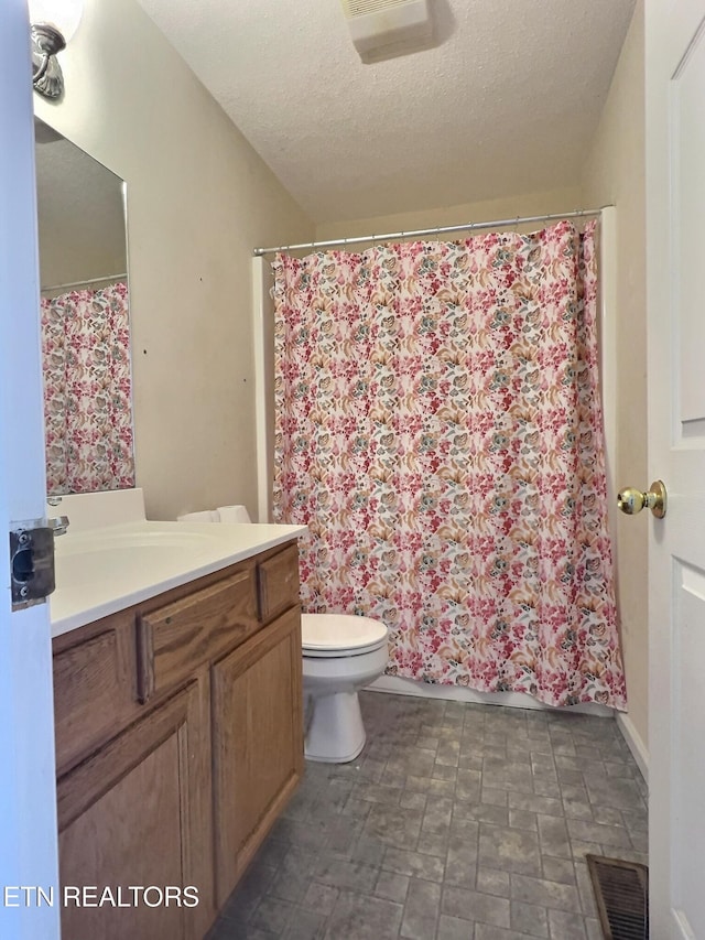 bathroom with curtained shower, vanity, a textured ceiling, and toilet