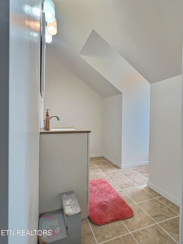 bathroom with tile patterned flooring, lofted ceiling, and sink