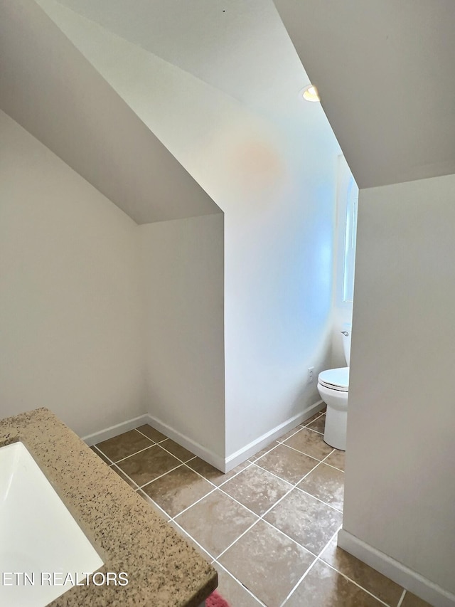 bathroom with toilet, vaulted ceiling, and tile patterned floors