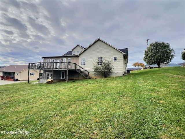 back of property featuring a deck and a lawn