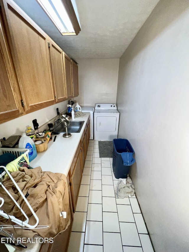 laundry area with sink, cabinets, washing machine and dryer, a textured ceiling, and light tile patterned floors