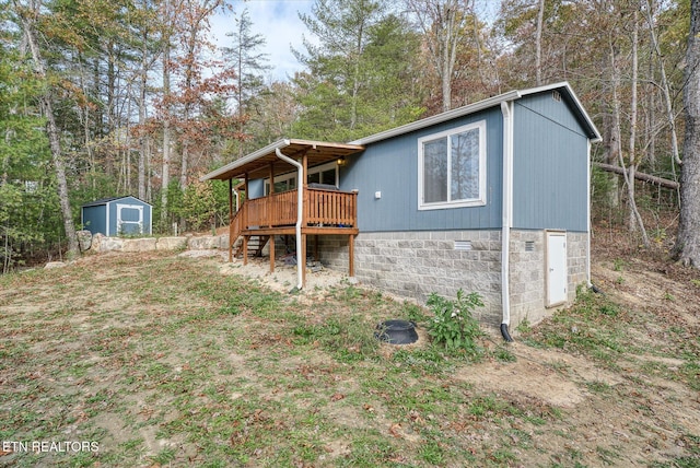 rear view of house with a shed and a deck