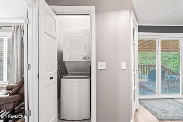 laundry area with stacked washer and dryer, plenty of natural light, and light hardwood / wood-style flooring