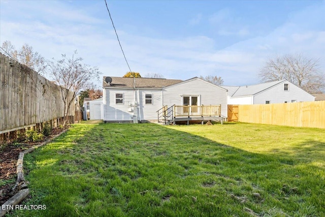 back of house featuring a lawn, an outdoor structure, and a deck