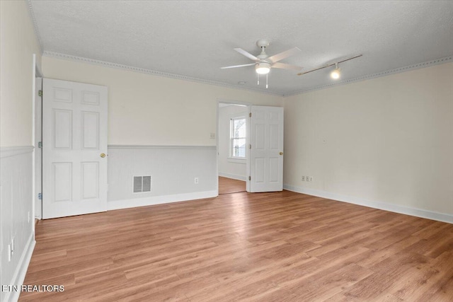 empty room with ceiling fan, light hardwood / wood-style floors, ornamental molding, and a textured ceiling