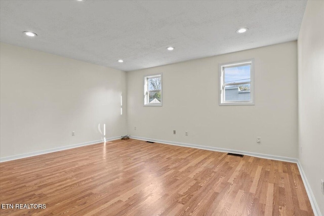 unfurnished room featuring a textured ceiling and light hardwood / wood-style flooring