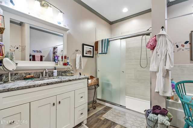 bathroom with hardwood / wood-style floors, vanity, a shower with shower door, and crown molding