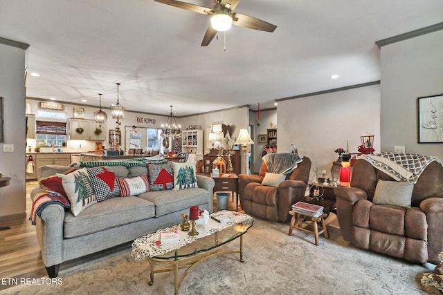 living room featuring hardwood / wood-style floors, ceiling fan with notable chandelier, and ornamental molding