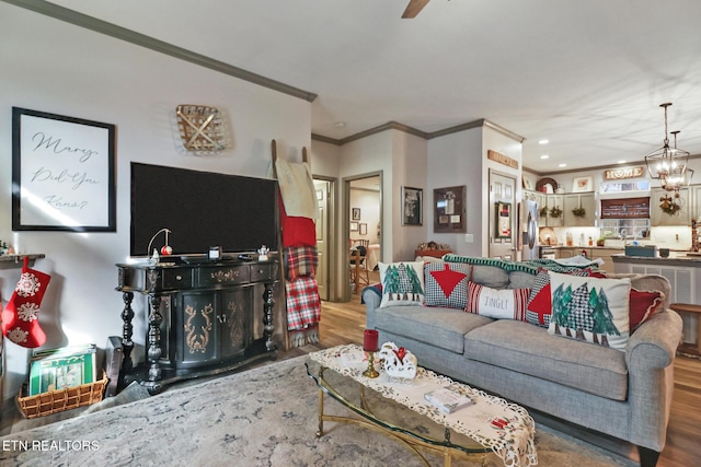 living room featuring crown molding, ceiling fan with notable chandelier, and hardwood / wood-style flooring