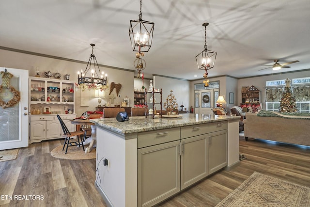 kitchen featuring pendant lighting, ceiling fan, light stone counters, an island with sink, and dark hardwood / wood-style flooring