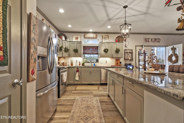 kitchen with tasteful backsplash, stainless steel appliances, stone countertops, light hardwood / wood-style flooring, and hanging light fixtures