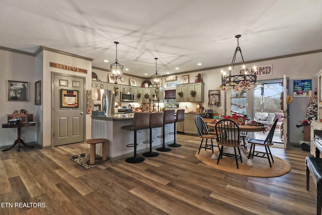 kitchen with dark wood-type flooring, appliances with stainless steel finishes, hanging light fixtures, and ornamental molding