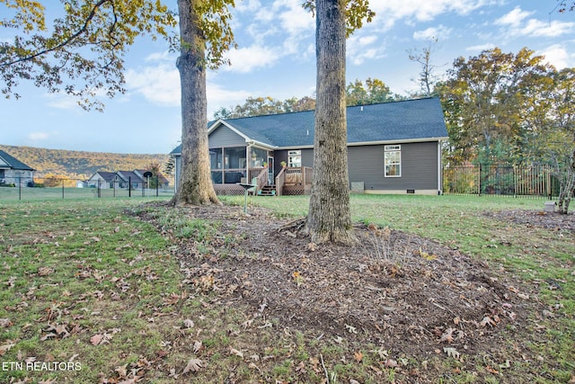 view of front facade with a sunroom, a wooden deck, and a front yard