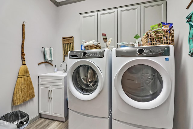 clothes washing area featuring sink, cabinets, ornamental molding, light hardwood / wood-style floors, and washer and dryer