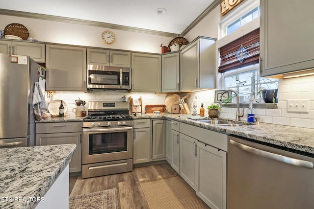 kitchen featuring sink, dark hardwood / wood-style floors, stainless steel appliances, light stone countertops, and decorative backsplash