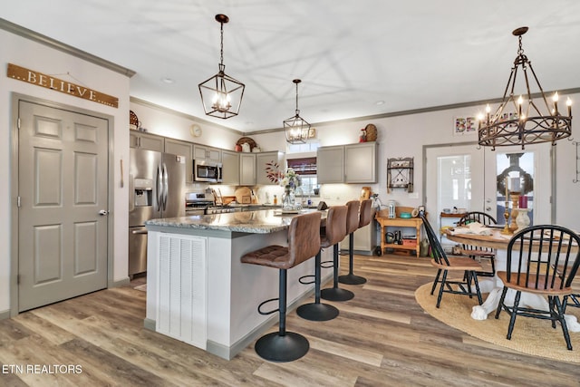 kitchen with a center island, hanging light fixtures, dark stone counters, gray cabinets, and stainless steel appliances