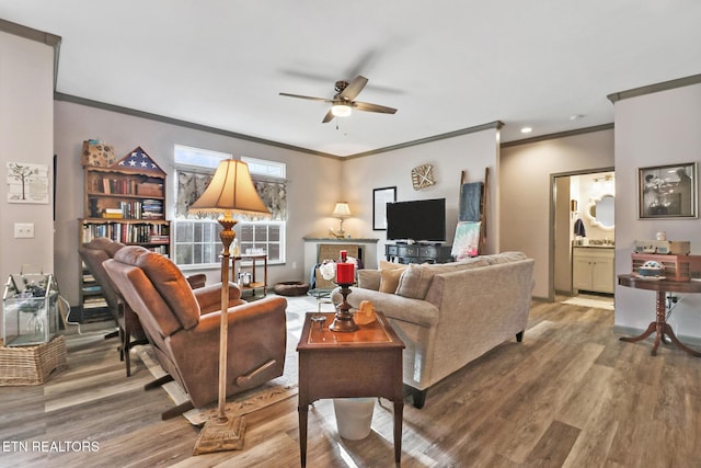 living room featuring hardwood / wood-style flooring, ceiling fan, and ornamental molding