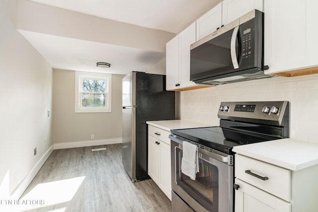 kitchen featuring backsplash, white cabinetry, light wood-type flooring, and appliances with stainless steel finishes