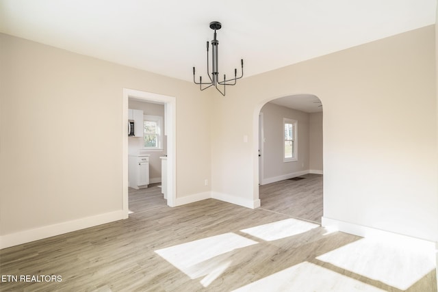 spare room with light wood-type flooring and a notable chandelier