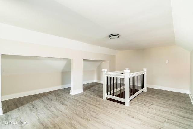 additional living space with light hardwood / wood-style flooring and lofted ceiling