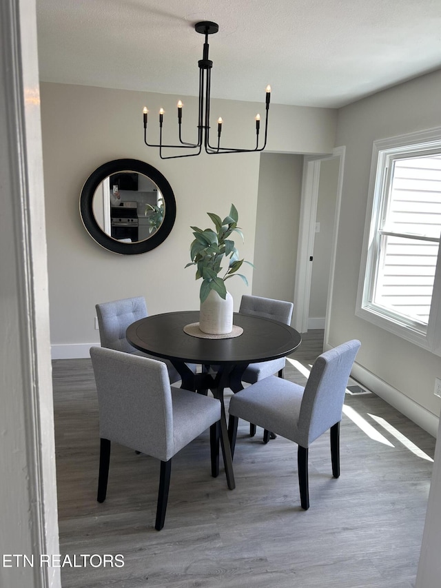 dining room with a chandelier, wood finished floors, and baseboards