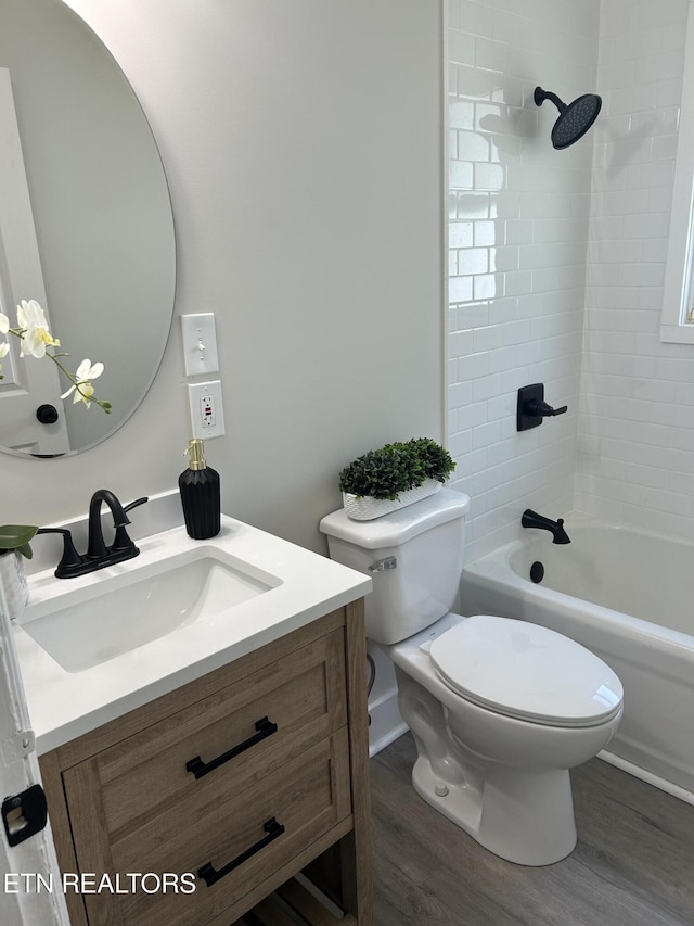 full bath with toilet, wood finished floors, vanity, and shower / tub combination