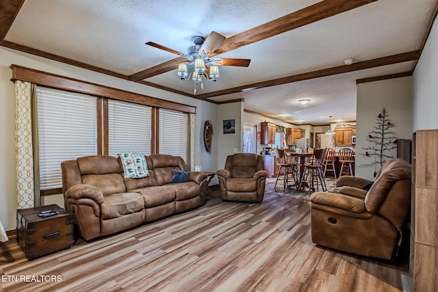 living room featuring ceiling fan, beam ceiling, a textured ceiling, and light hardwood / wood-style flooring