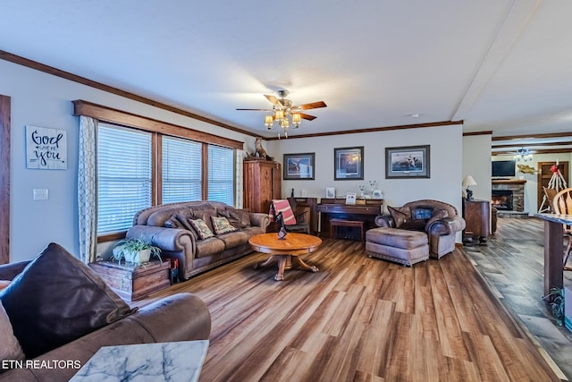 living room featuring a stone fireplace, ceiling fan, wood-type flooring, and ornamental molding