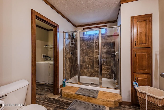 bathroom featuring hardwood / wood-style floors, toilet, washing machine and dryer, a textured ceiling, and a shower with shower door