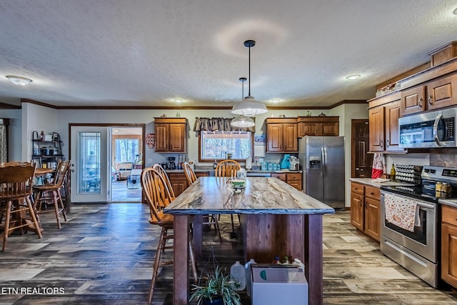 kitchen featuring appliances with stainless steel finishes, a center island, a textured ceiling, and hardwood / wood-style floors