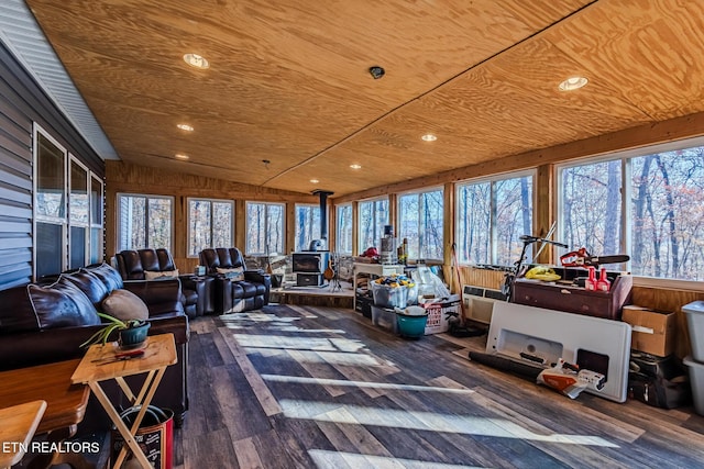 sunroom with a wood stove, vaulted ceiling, a healthy amount of sunlight, and wood ceiling