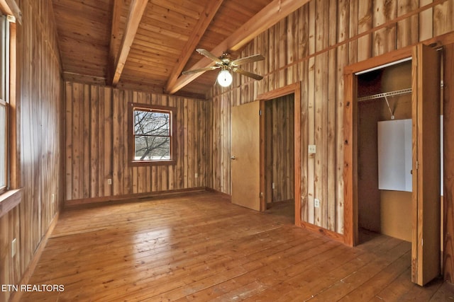 spare room with hardwood / wood-style flooring, wooden walls, wooden ceiling, ceiling fan, and lofted ceiling with beams