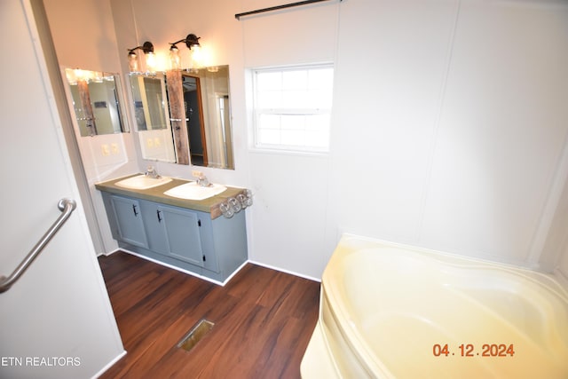 bathroom with hardwood / wood-style flooring, vanity, and a tub