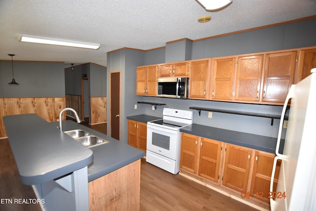 kitchen with white appliances, crown molding, sink, wood-type flooring, and pendant lighting