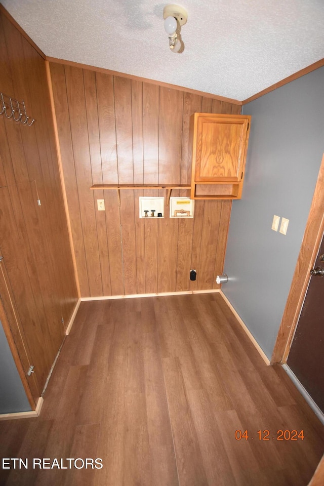 laundry area featuring wooden walls, hardwood / wood-style floors, washer hookup, and a textured ceiling